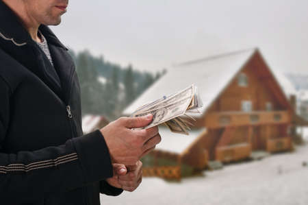 Man with money buying cheap wooden mountain cottageの写真素材