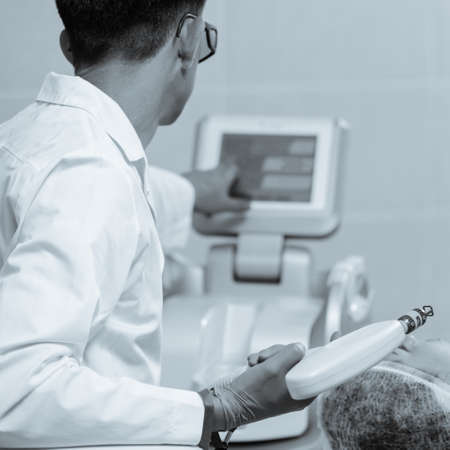 Male therapist using modern Harmony XL machine facial treatment. black and white image with blue...