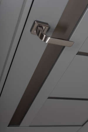 Closeup photo of chrome handle on gray door with framesの写真素材