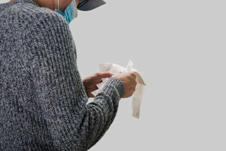 Upset man in protective mask holding grocery receipt in handsの写真素材