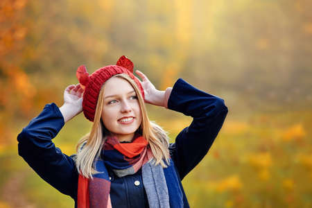 Pretty smiling woman holding autumn leaves like ears