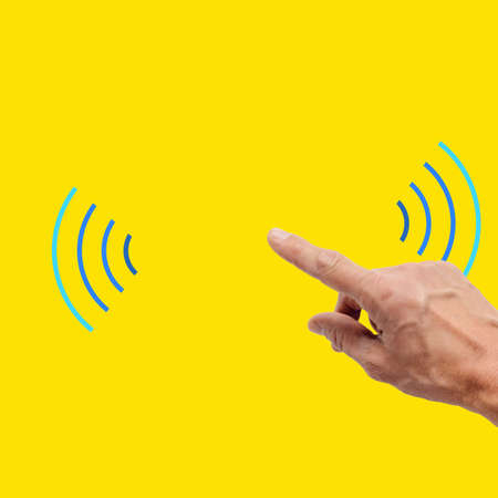 Male hand using free wifi hotspot isolated on yellow backgroundの写真素材