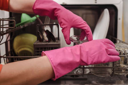 Closeup of woman in protective gloves washing dishes in the dishwasherの写真素材