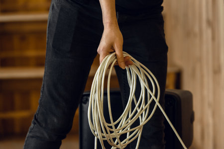 Closeup of male musician holding white extension cord in music studioの写真素材
