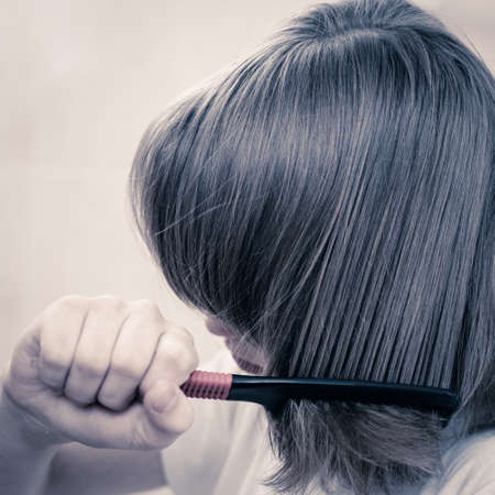 Teenager boy brushing hair with comb at home bathroomの写真素材