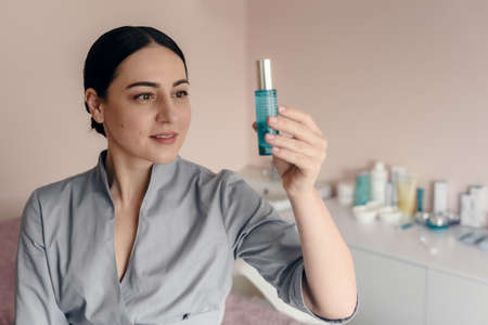 Professional cosmetologist in beauty salon showing cream for skincare treatmentの写真素材