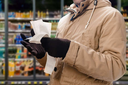 Closeup photo of shocked man looking at store receiptの写真素材