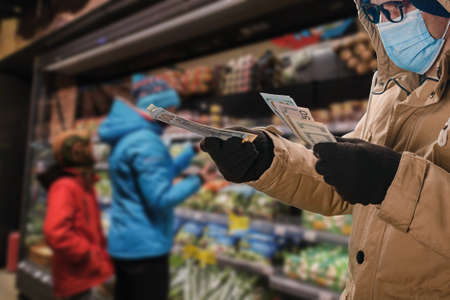Man in medical mask stretching out his hand with money, for the concept of product price changes