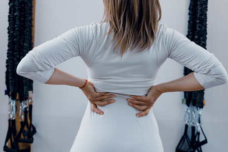 Fit athletic woman suffering back ache after exercisingの写真素材