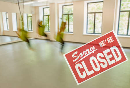 inscription sorry we are closed. compliance with sanitary measures during a pandemic. Group of young women making antigravity yoga exercises, persons are in moving.の写真素材