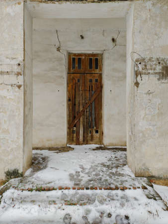 Old door boarded up with wooden planks in abandoned houseの写真素材