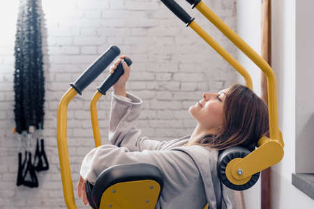 Bored lazy sportive woman trying training on fitness machine in gym