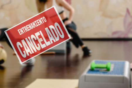 in Spanish inscription sorry workout canceled. training cancellation due to business closure. Closeup of healthy sporty woman training with step platformの写真素材