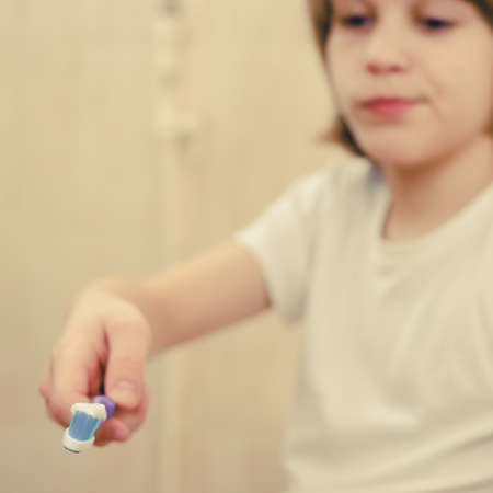 Blurred photo of handsome smiling young boy with toothbrush in hand. focus on toothbrushの写真素材
