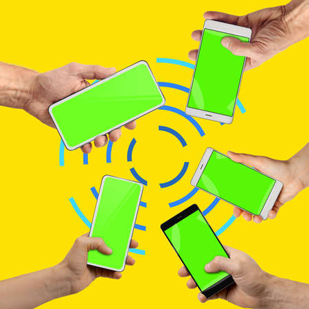 Set of people hands holding mobile devices with chromakey screens emitting wi-fi on yellow...