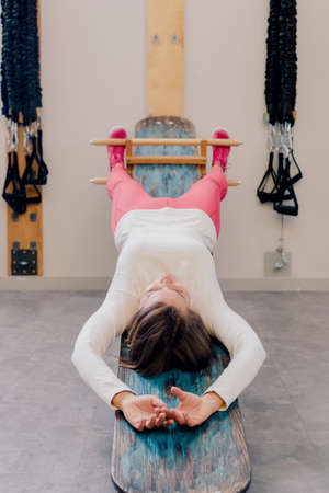 Middle age sporty woman doing back workout on fitness exercise machineの写真素材