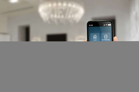 Man holding modern mobile phone connecting to house devices with smart home automation appの写真素材