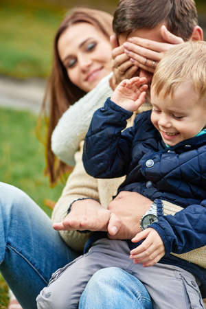 Portrait of joyful young family having fun and playing games in parkの写真素材