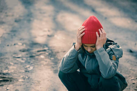 Portrait of young teenager boy having problem and sitting outdoor with hands on headの写真素材