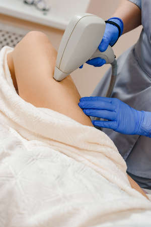 Professional beautician doing laser treatment and removing hair from female legの写真素材