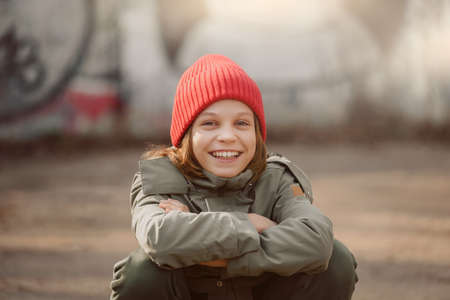 Happy smiling teen boy in red hat sitting outdoor in cityの写真素材