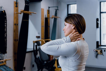 Sporty woman feeling pain after training and sporty woman touching her neckの写真素材