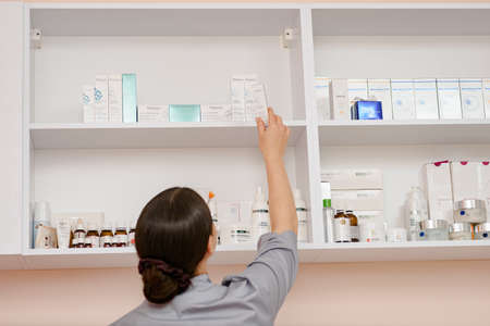 Dnepr, Ukraine- April 20, 2021: Female beauty doctor looking for new cosmetic cream on showcase in beauty salonのeditorial素材