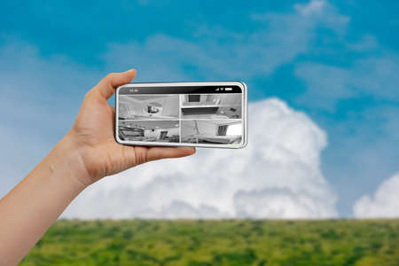 Female hand holding smartphone and monitoring video footage against blue sky mountain background