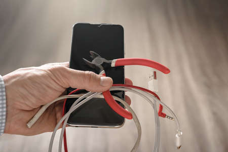 Mans hand with cutters showing concept of wireless use of mobile gadgets