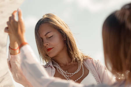 Attractive fashionable mature woman posing with miror on beachの写真素材