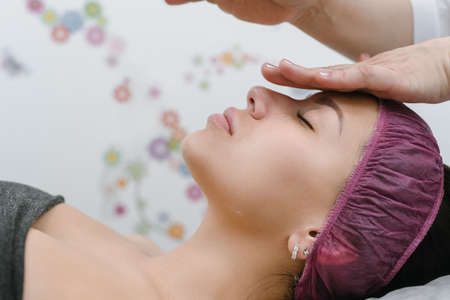 Cosmetologist doing anti-aging face massage for young woman in spa salonの写真素材