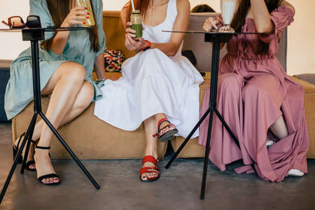 Closeup photo legs of three stylish ladies spending time together in cafeの写真素材