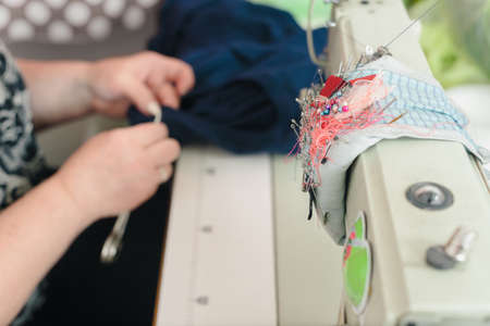Closeup photo of female tailor making garment in her workplaceの写真素材