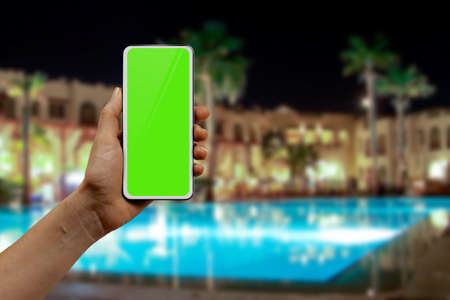woman using roaming internet on smartphone while traveling abroad, green chromakey display