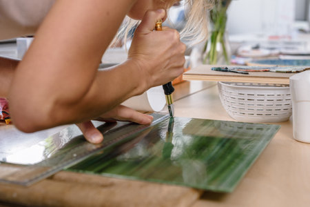 Young artistic woman cutting glass for mosaic making master classの写真素材