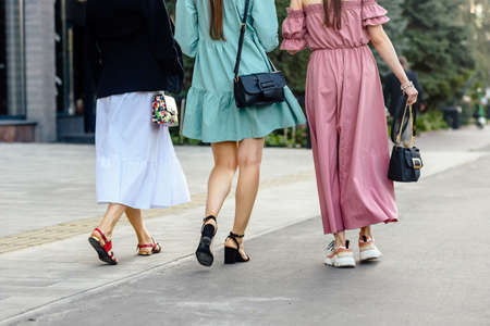 Closeup photo legs of three female friends walking together in city and having funの写真素材