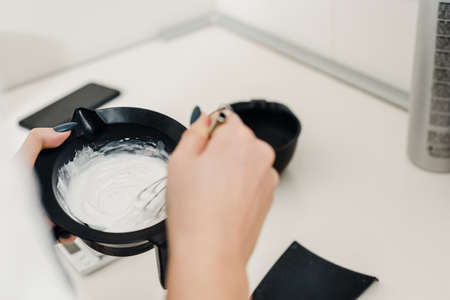 Closeup photo of female hair stylist mixing hair dye in a bowlの写真素材