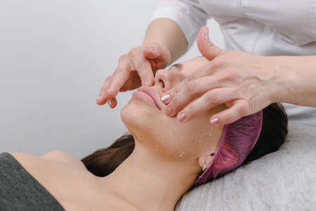 Beautician massaging face of beautiful woman in modern spa salonの写真素材