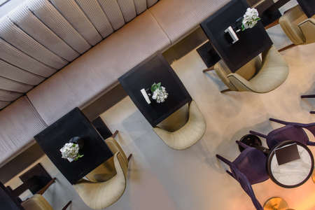 Luxury restaurant with wooden tables, flowers and brown armchairs made of leather