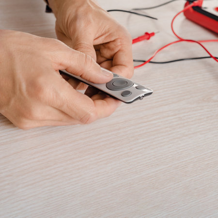 Closeup photo of male repairman checking remote control with digital multimeter at home