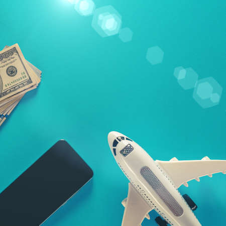 Flight booking and online check-in concept, dollar bills smartphone and airplane model on blue backgroundの写真素材