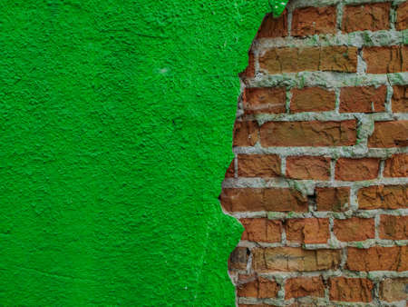 Old cracked brick wall with falling off flakes of green plasterの写真素材