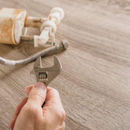 Male technician plumber using wrench to repair tube, closeup photoの写真素材