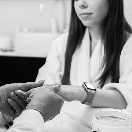 Young attractive girl receiving hand scrub peeling in beauty salon, black and white imageの写真素材