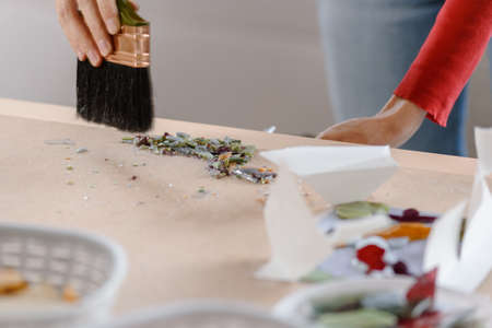 Female artist cleaning mess on her workplace and sweeping dust after mosaic makingの写真素材