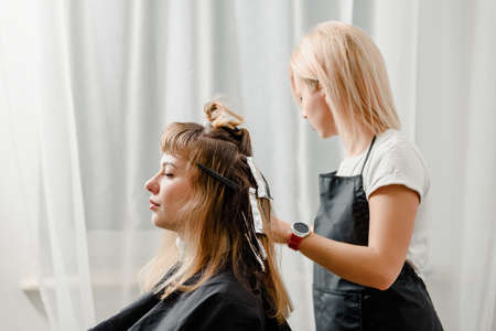 Young female hairdresser coloring clients hair in beauty studioの写真素材