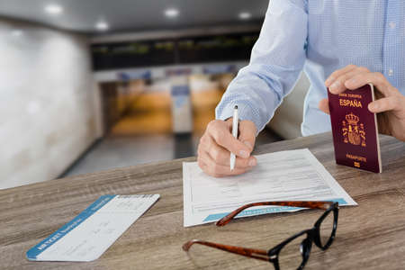 Man filling travel insurance application form with boarding pass and hispanic passport. inscription...