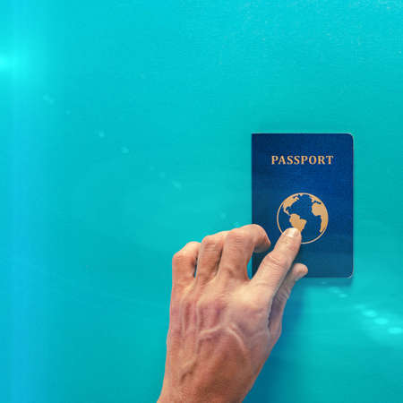Male tourist with international passport on blue backgroundの写真素材