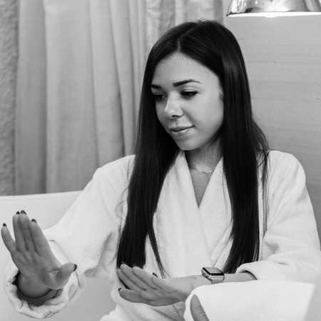 Happy young woman looking at her nails after professional treatment in beauty salon, black and white imageの写真素材