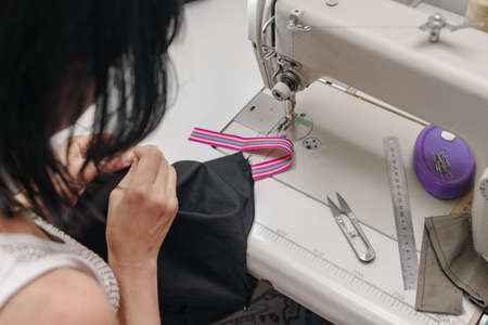 Female hands of professional tailor stitching black fabricの写真素材